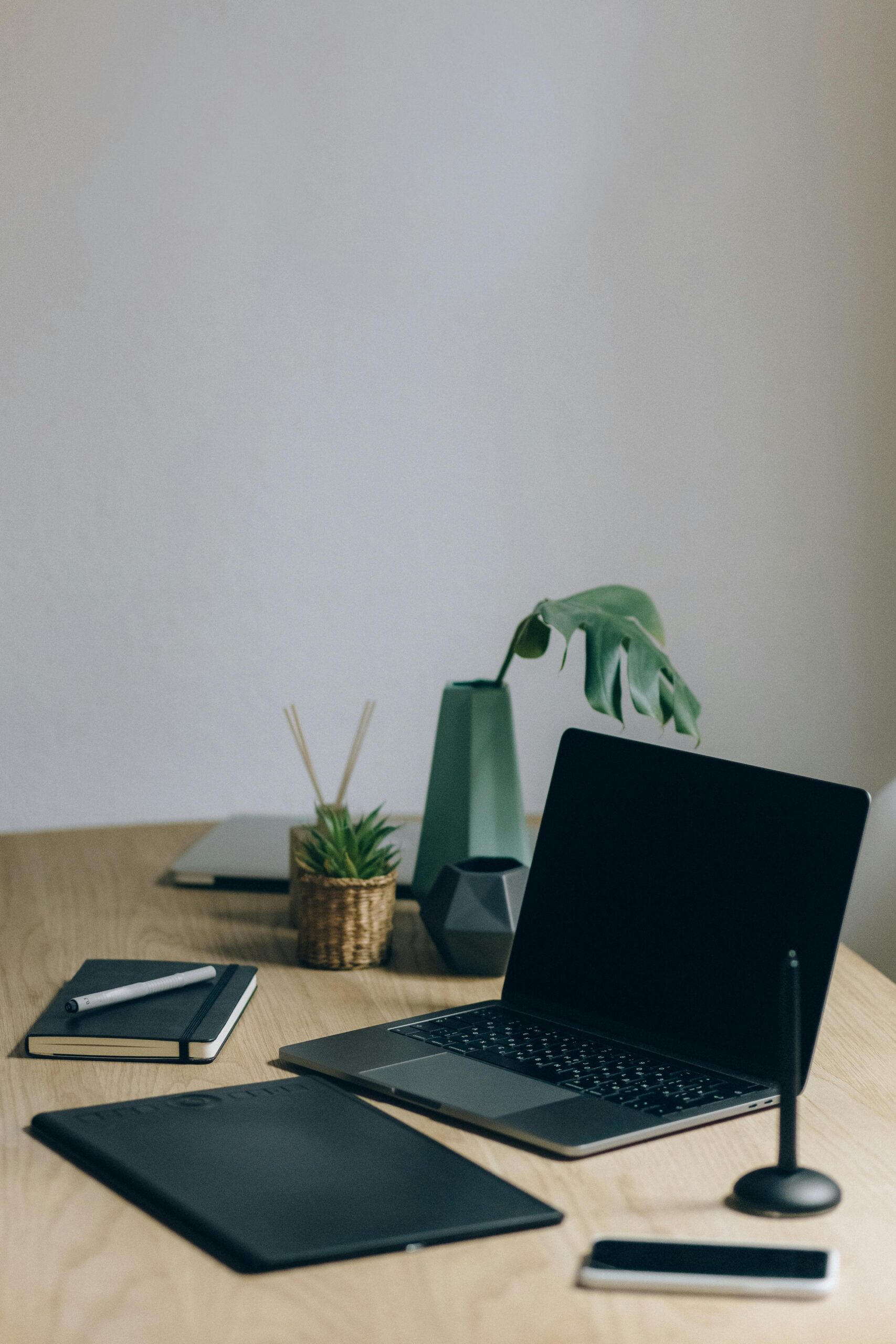 pexels-photo-5412270-5412270 A minimalist home office setup featuring a laptop, notebook, and plant for a productive workspace.
